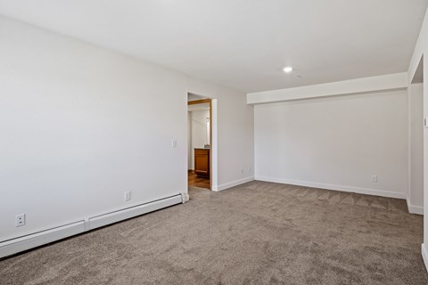 A spacious room with a carpeted floor and white walls.