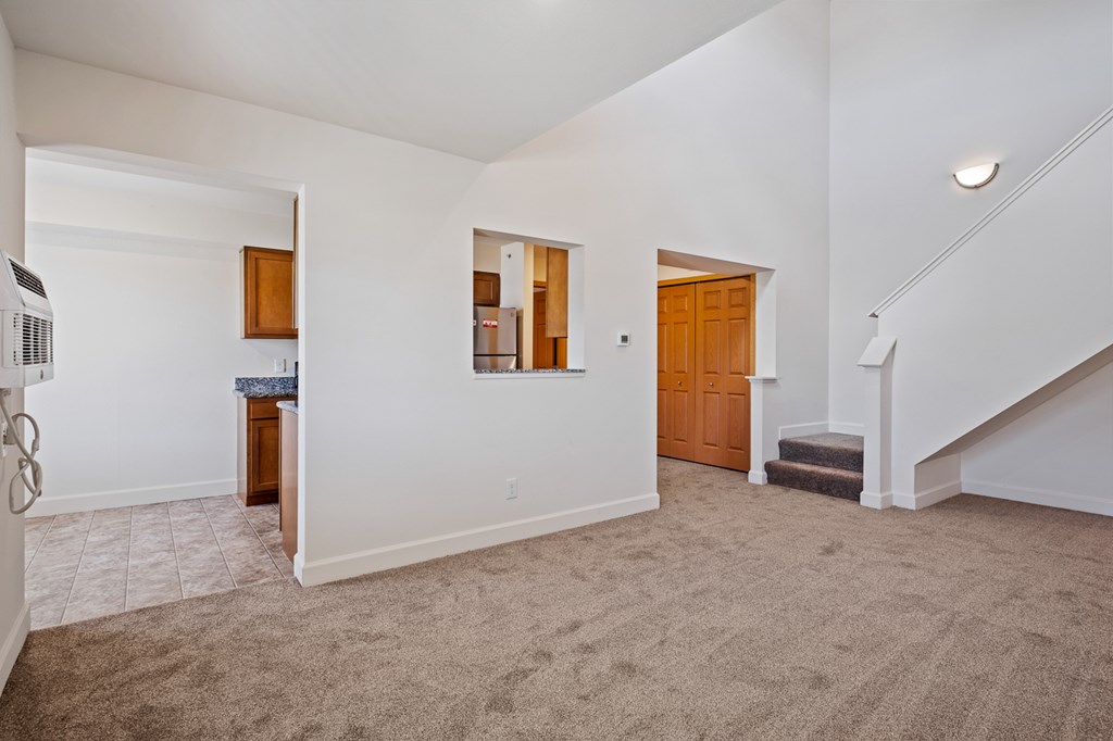 A spacious room with a staircase and a door.