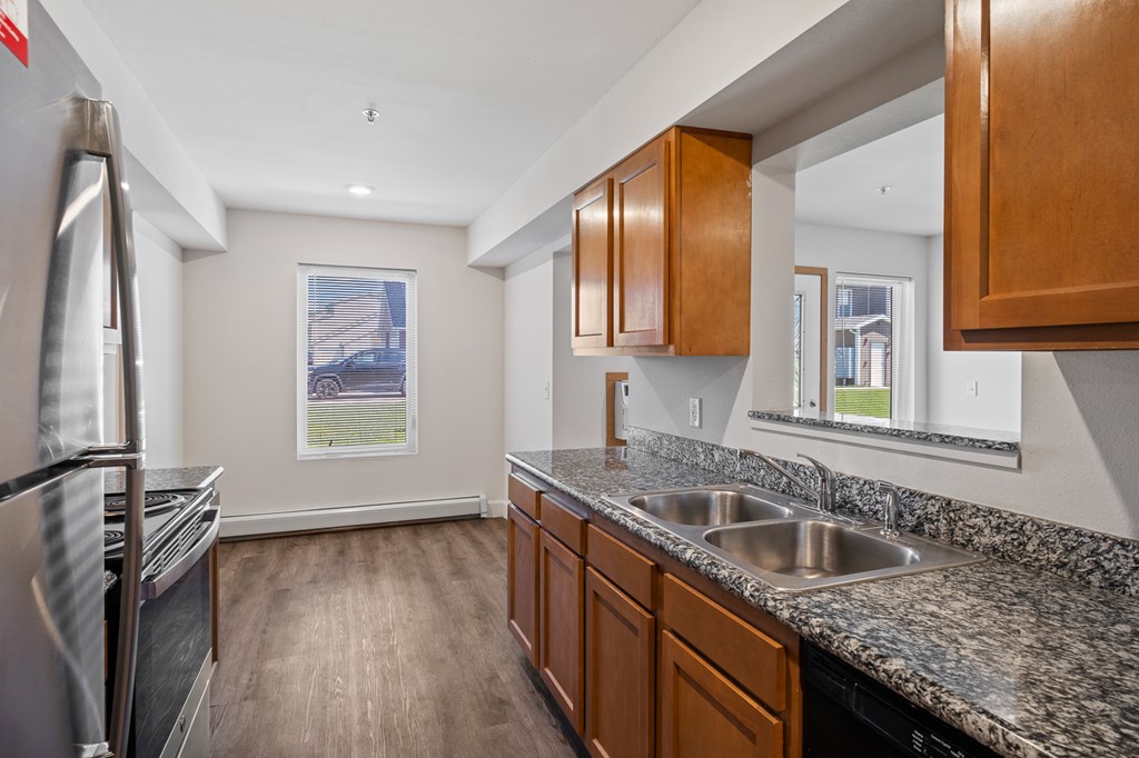 A kitchen with a granite counter top and wooden cabinets.