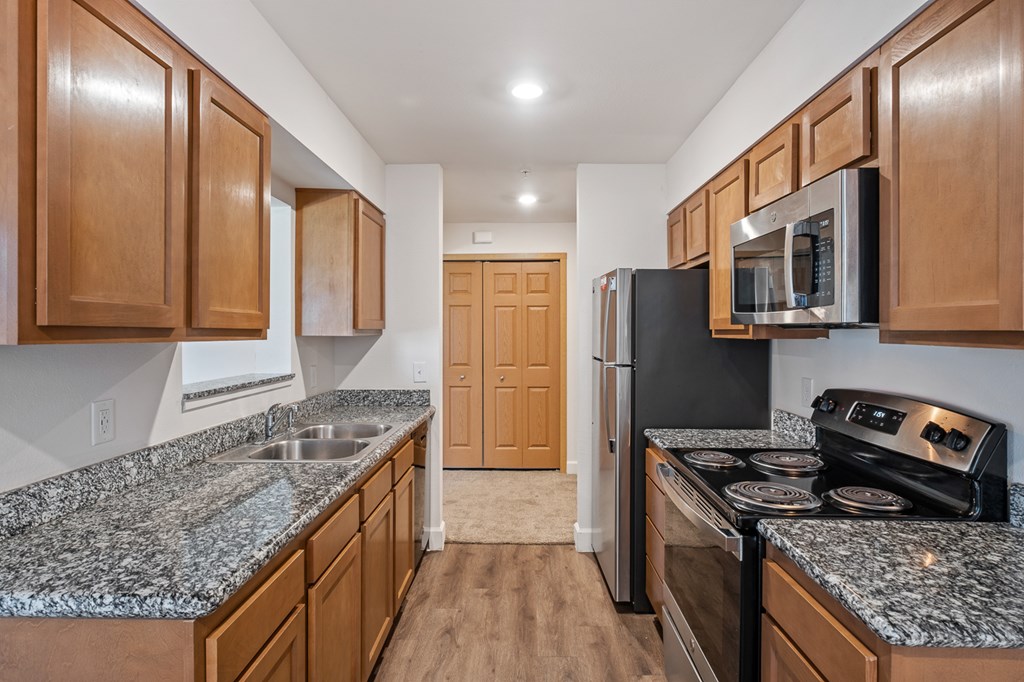 A kitchen with granite countertops and wooden cabinets.