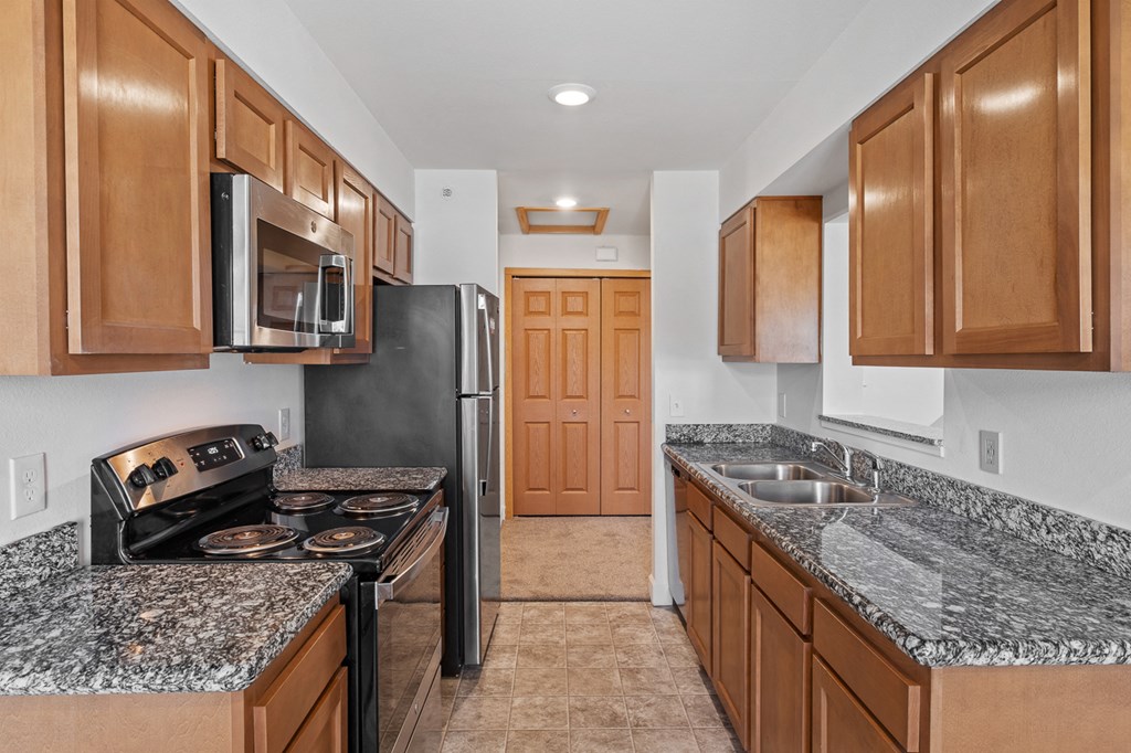 A kitchen with brown cabinets and a black refrigerator.