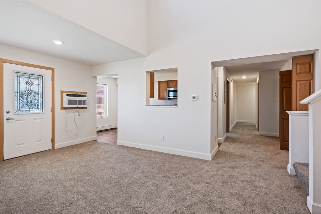 A spacious living room with a carpeted floor and white walls.