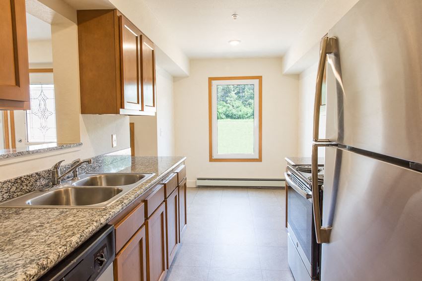 a kitchen with granite counter tops and a stainless steel refrigerator