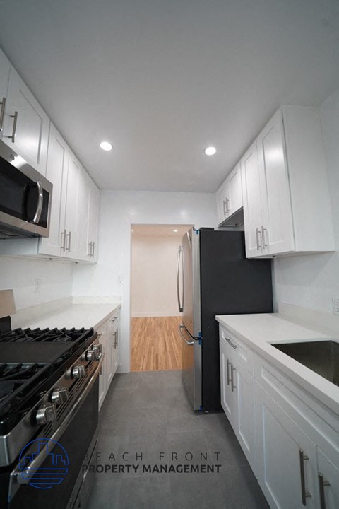A modern kitchen with white cabinets and a black stove top oven.