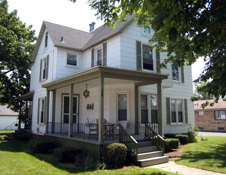 a white house with a porch and a tree