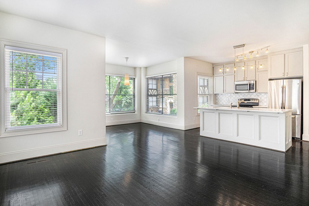 an empty kitchen with white cabinets and a large window