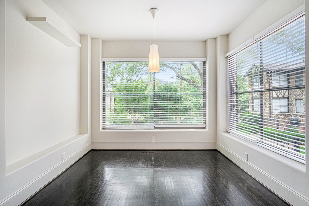 an empty living room with large windows and dark wood floors