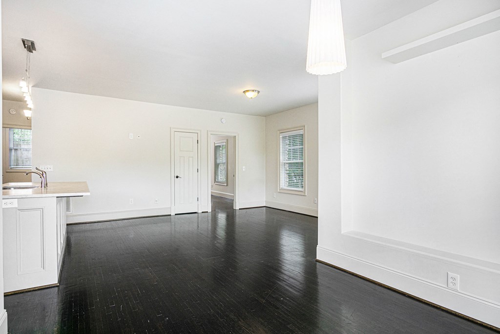 a renovated living room and kitchen with white walls and dark wood floors