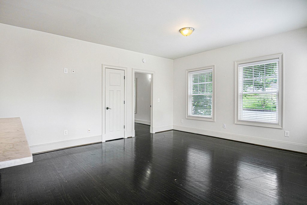 an empty living room with black wood floors and white walls