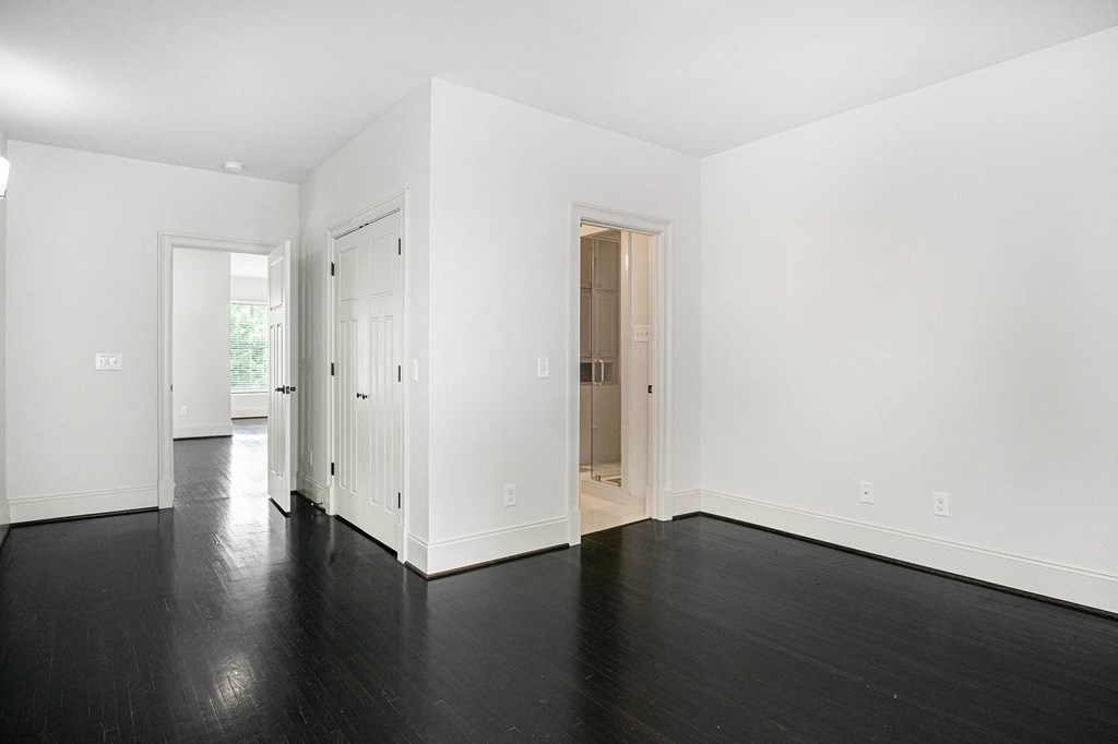 an empty living room with white walls and black wood floors
