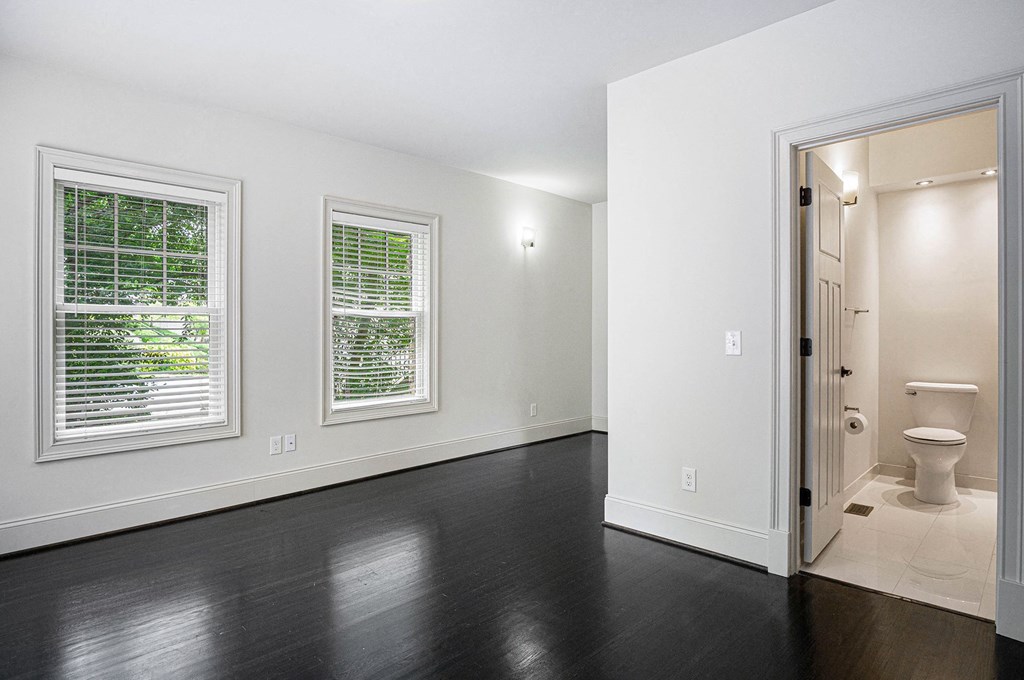 an empty room with a toilet and two windows
