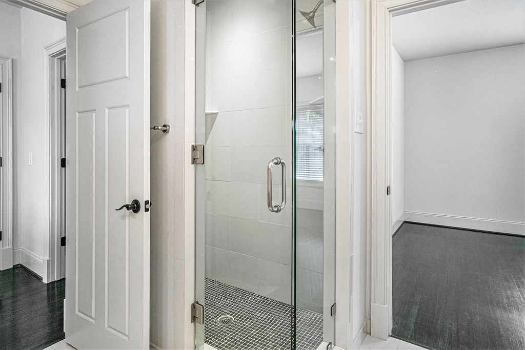 a bathroom with a glass shower and a white door