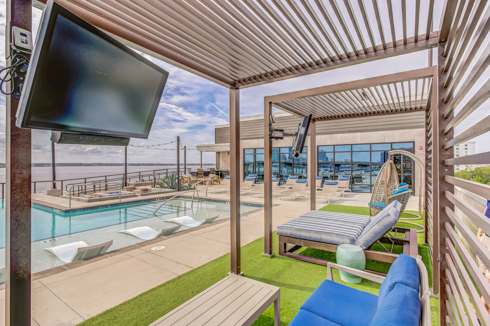 a patio with a pool and lounge chairs and a tv