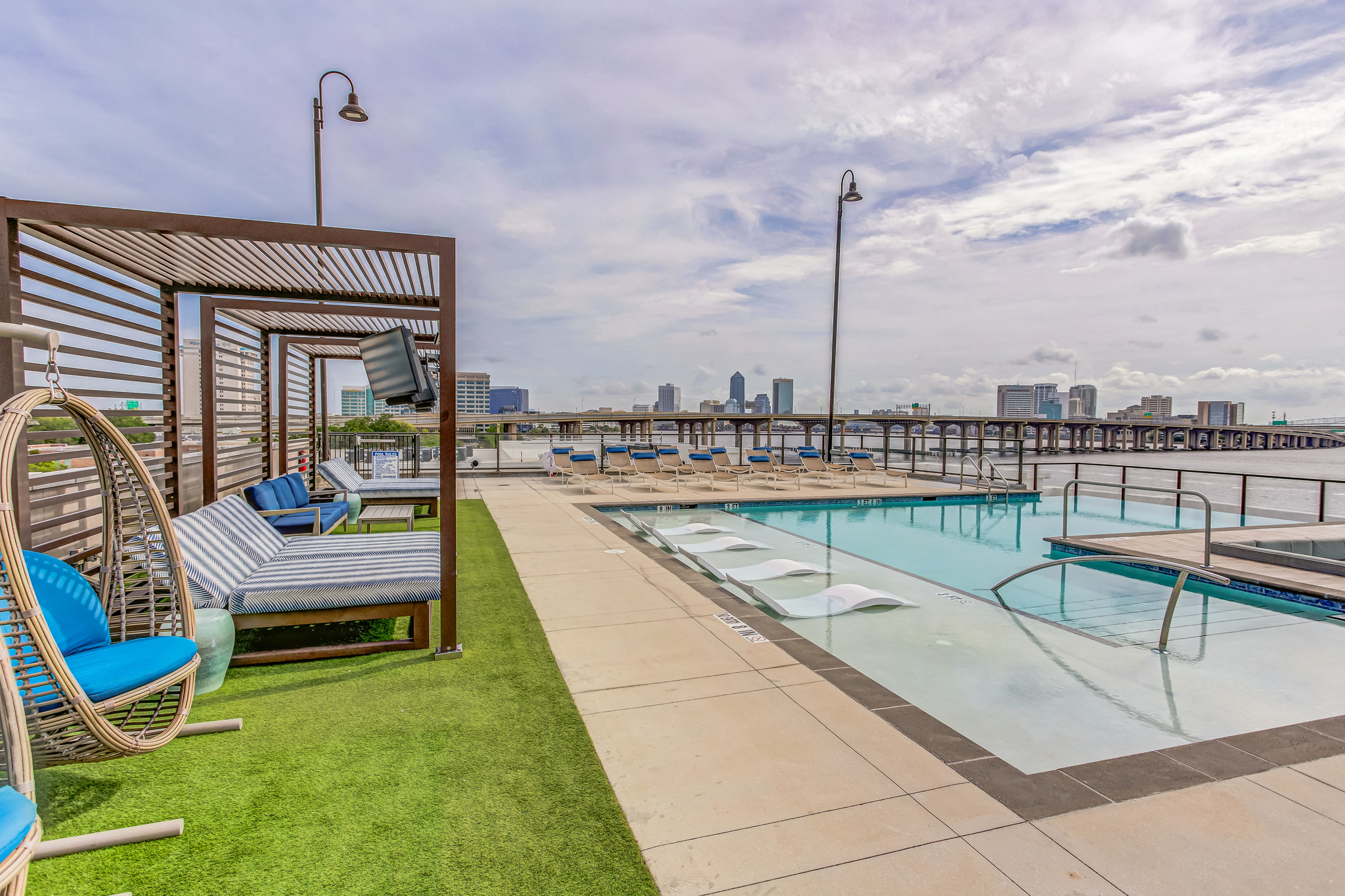a pool with lounge chairs and a city skyline in the background
