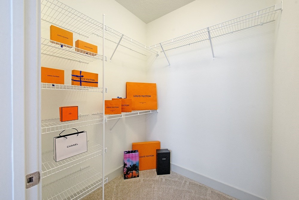a walk in closet with white walls and shelves with orange boxes