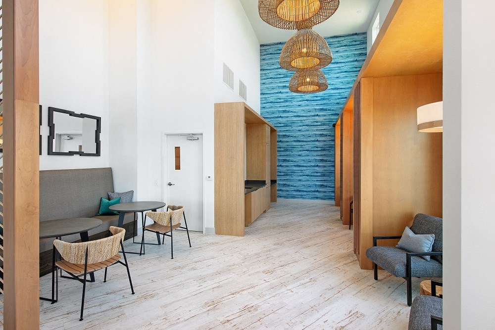 the lobby of a hotel with tables and chairs and a hallway with a blue wall
