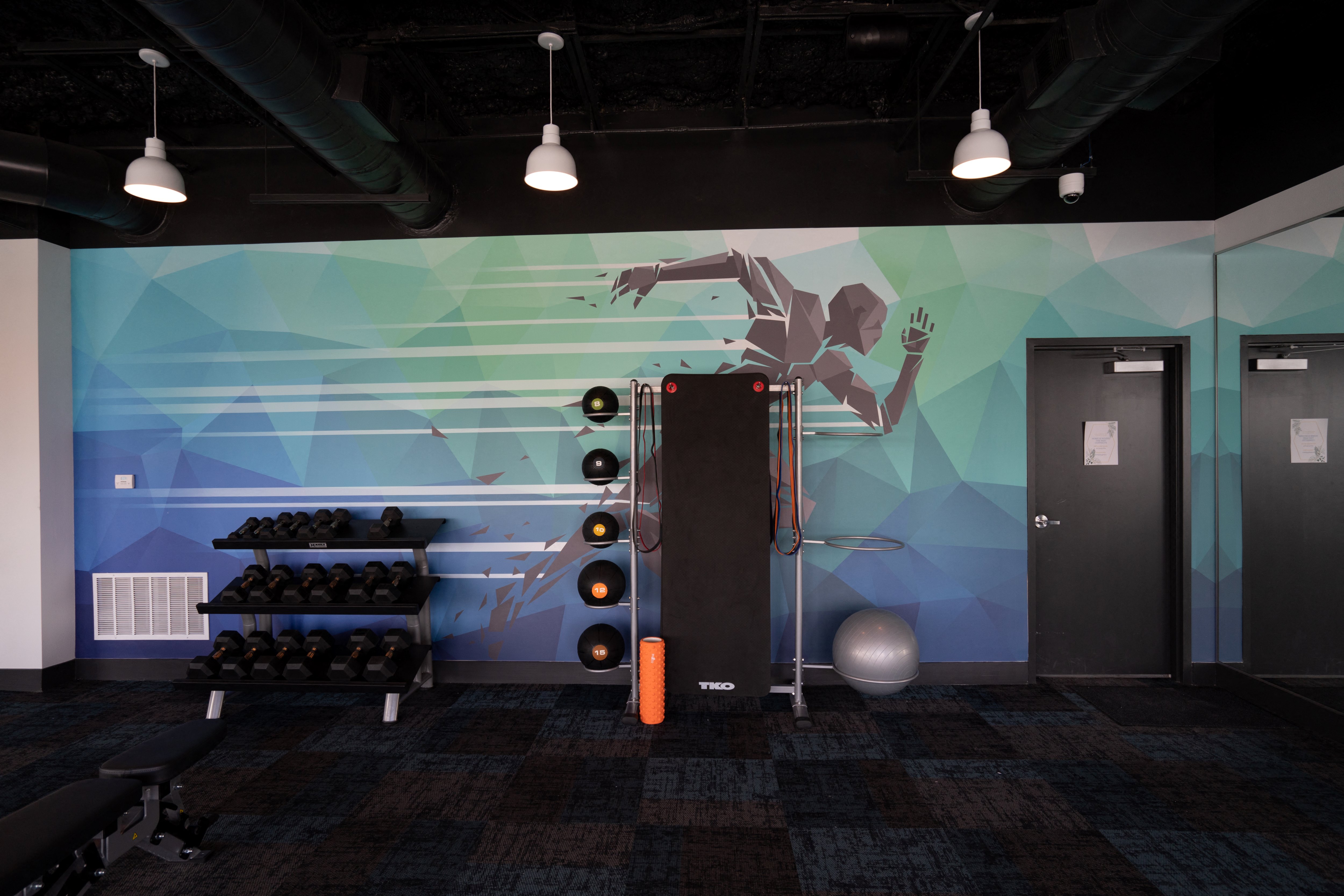 a fitness room with a wall mural of a man running in a gym