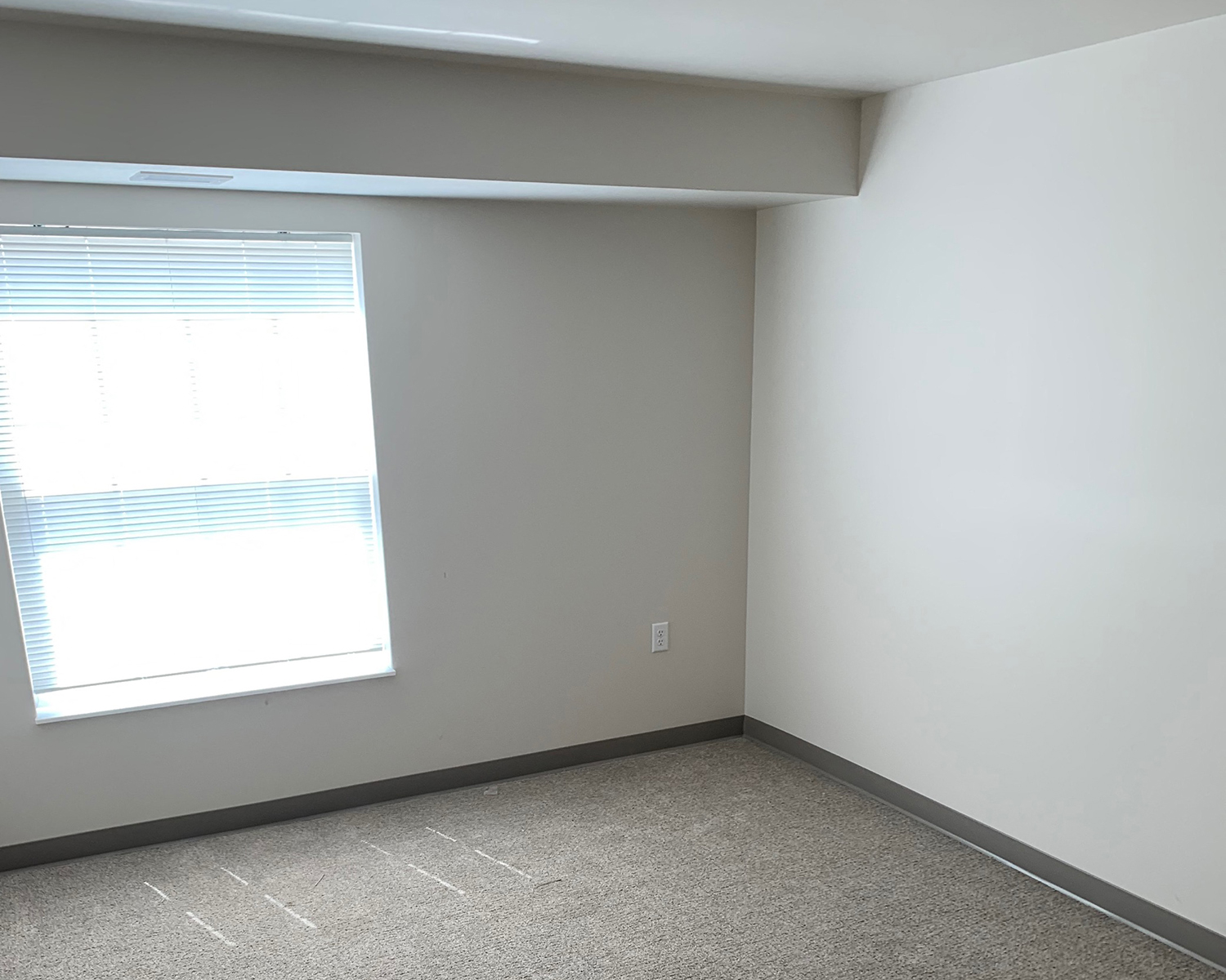 an empty room with a window and white walls
