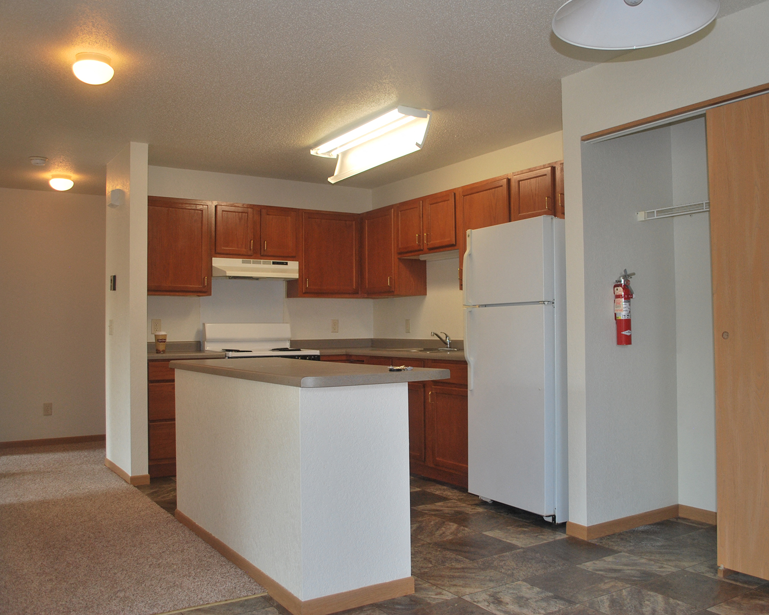 an empty kitchen with an island and a white refrigerator