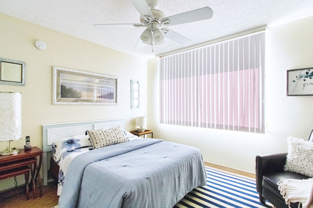 spacious bedroom with wood-style floor, large window, and ceiling fan
