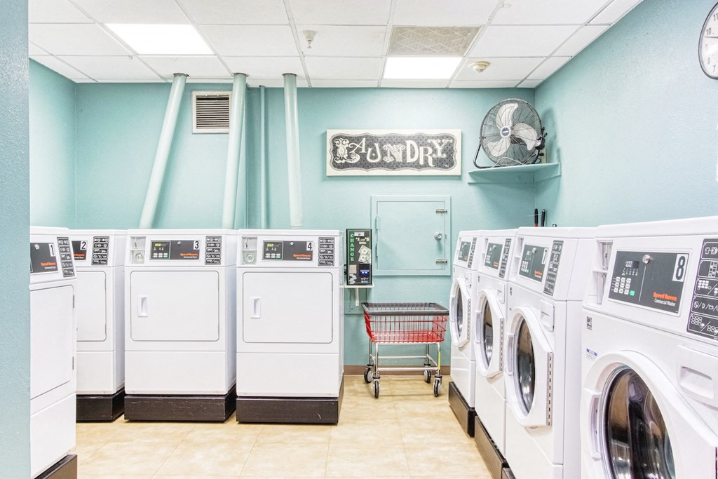 laundry room with washers and dryers, rolling cart, fan, and coin machine