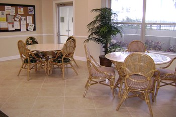 sitting area with tables, chairs, bulletin board, and large windows
