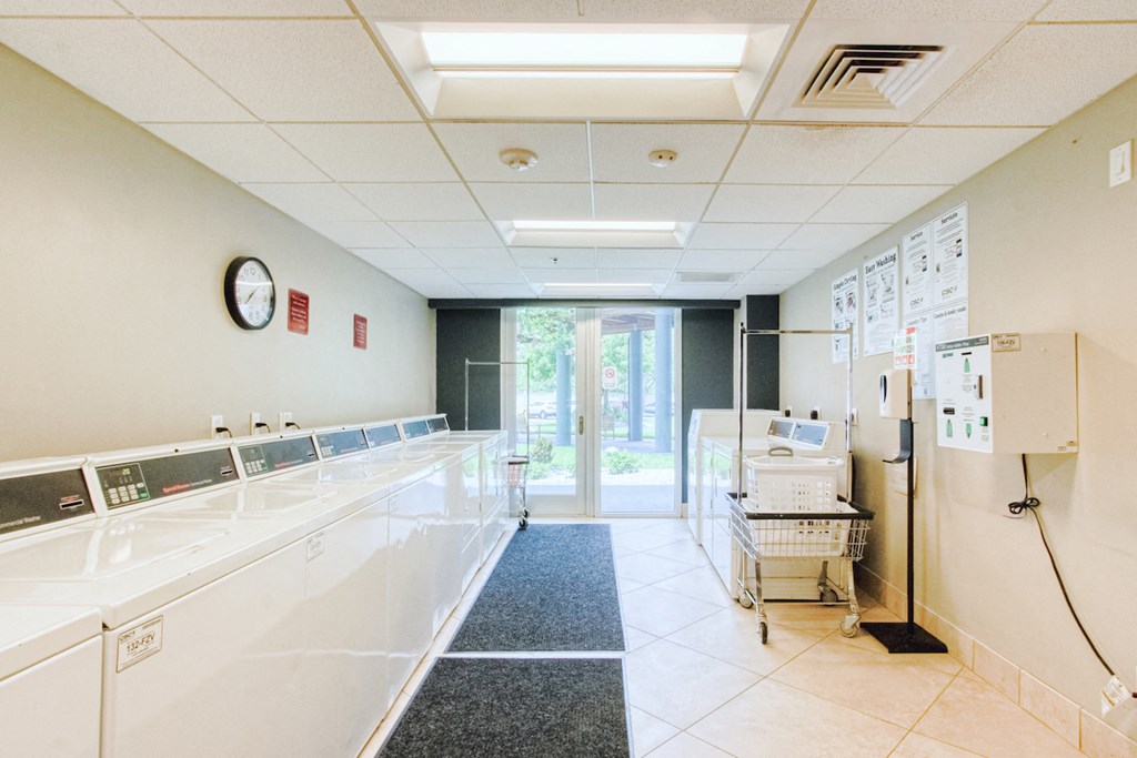 large laundry center with washers, dryers, and carts