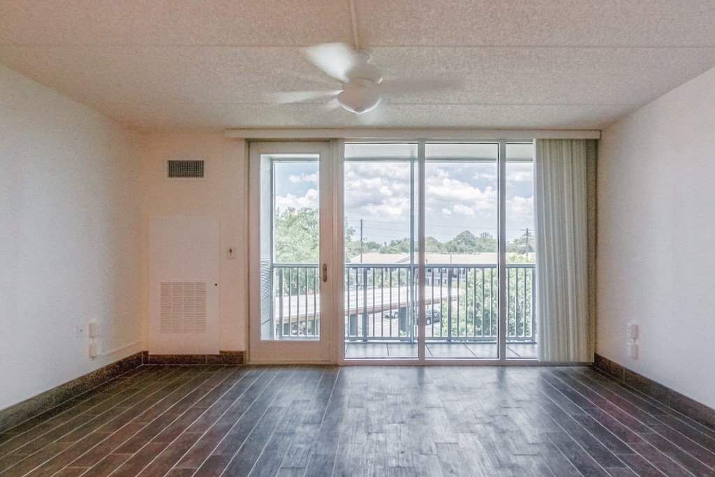 living room with ceiling fan, large windows, and door to balcony