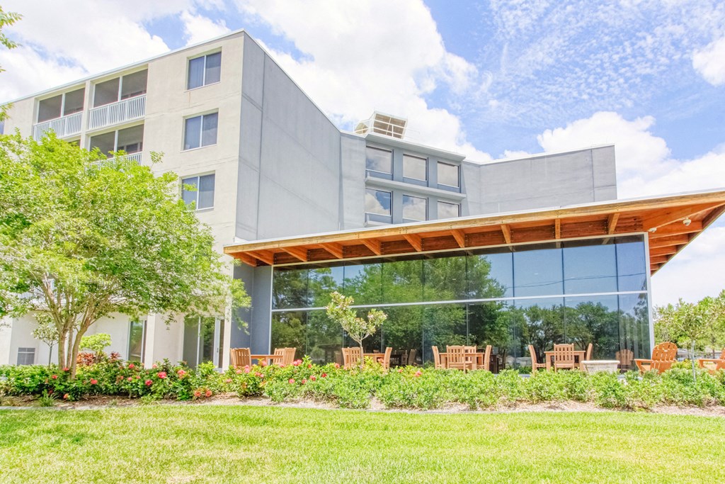 lush landscaping and outdoor seating in front of large lobby windows