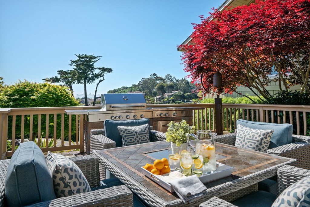 a patio with a table and chairs and a grill