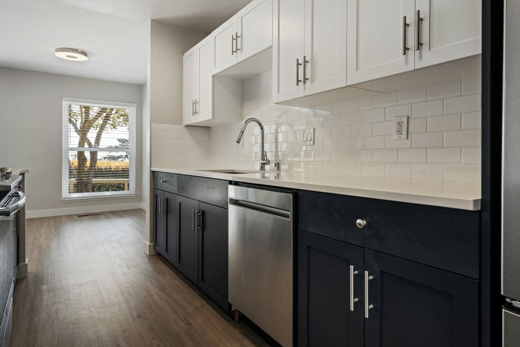 a large kitchen with white cabinets and a window
