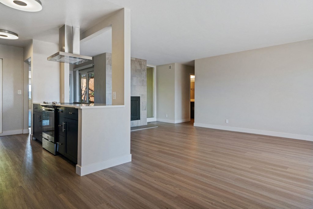 an empty living room and kitchen with a wood floor