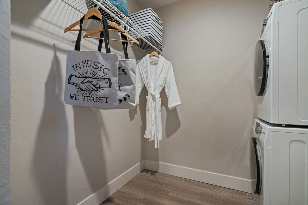 a laundry room with a white shirt and a tote bag hanging on the wall