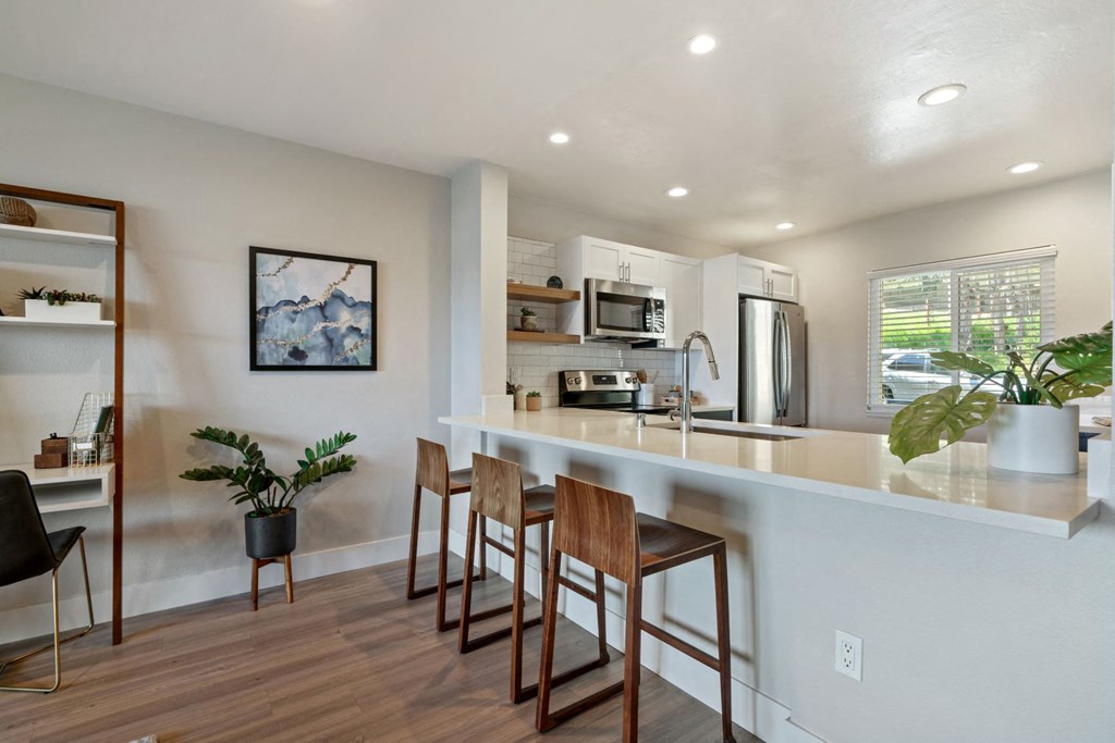 an open kitchen with a counter top bar and stools