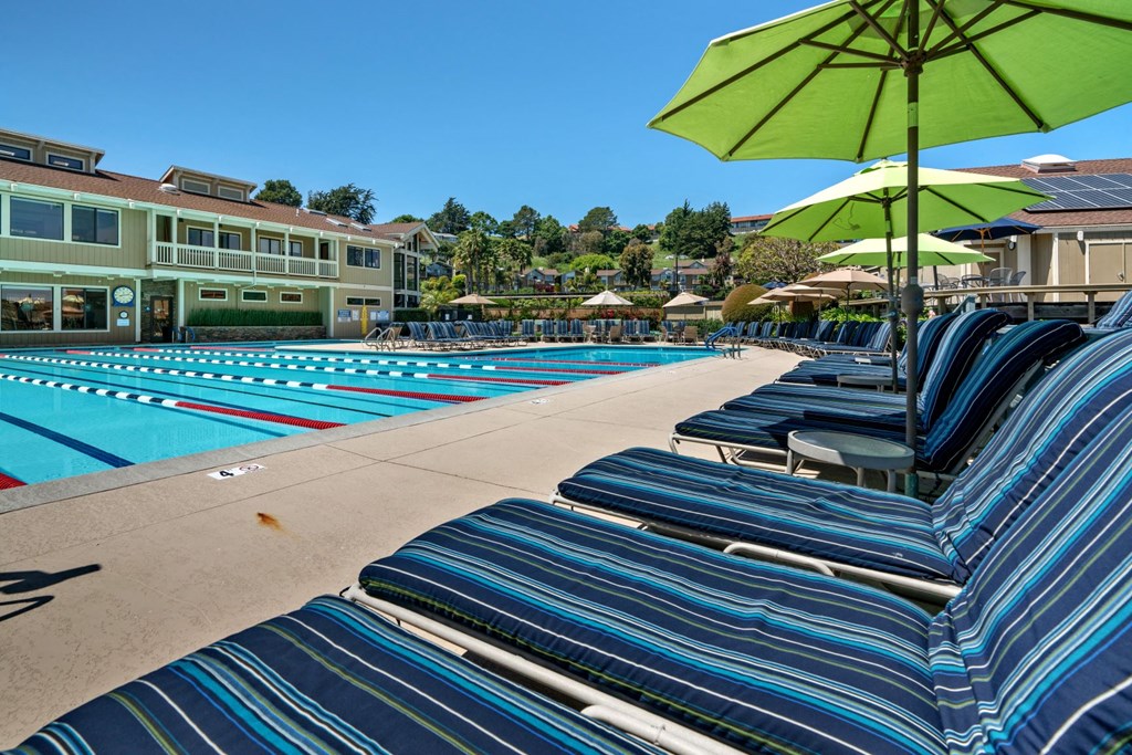 a view of a pool with lounge chairs and umbrellas