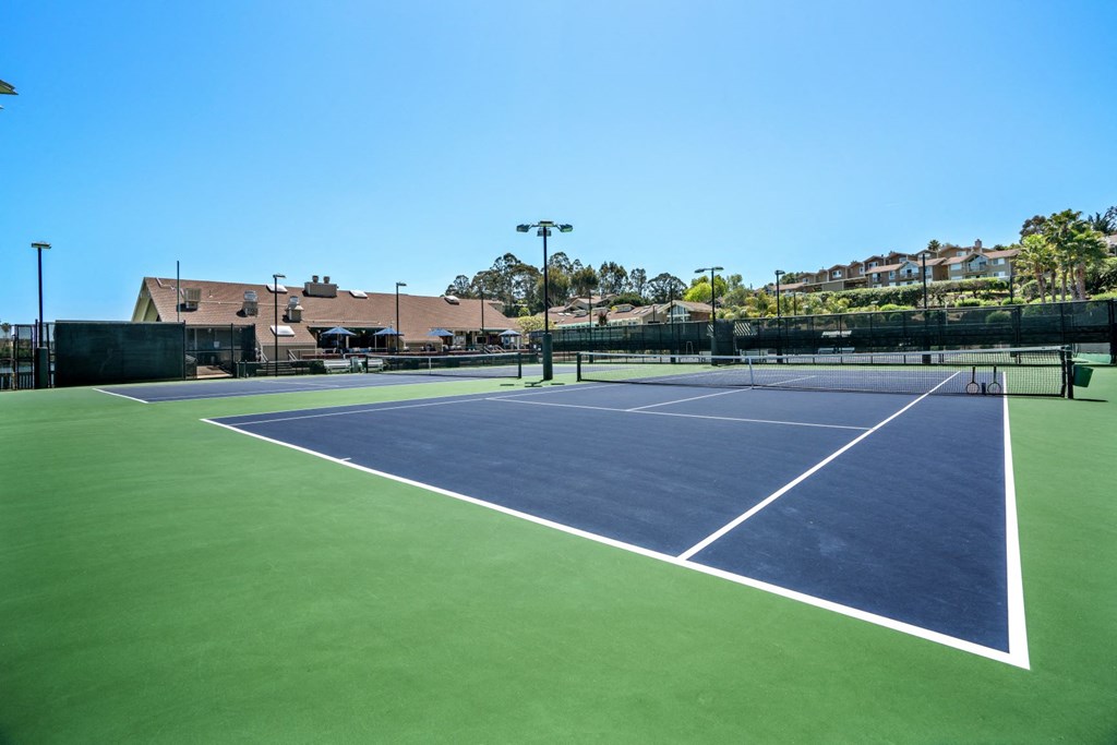 a blue and green tennis court with a building in the background