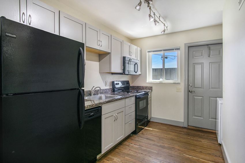 an empty kitchen with black appliances and white cabinets