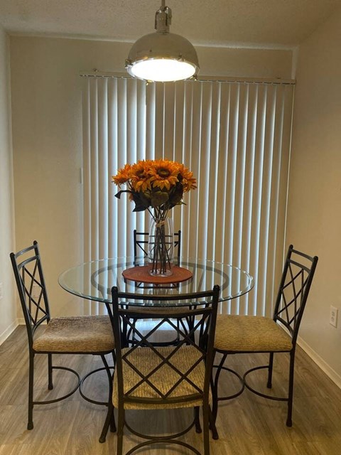 a dining room table with three chairs and a vase of flowers