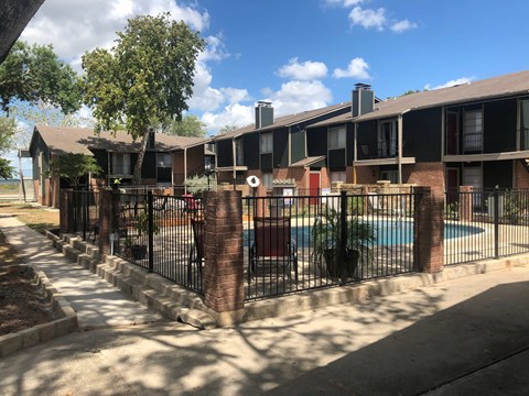an apartment building with a pool behind a fence