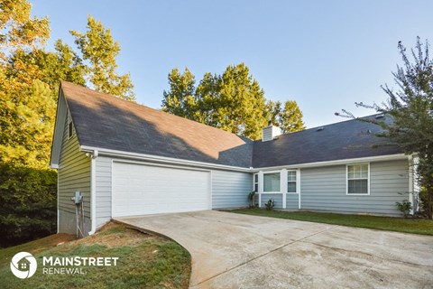 the front of a white house with a driveway and a car garage