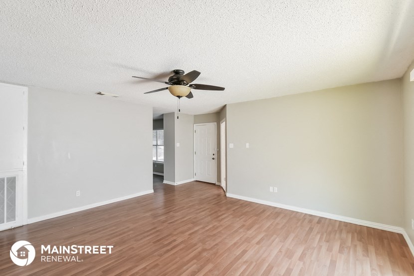 the spacious living room and dining room with wood flooring and a ceiling fan