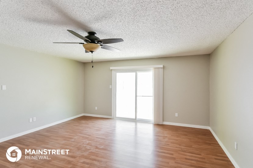the spacious living room with ceiling fan and wood flooring