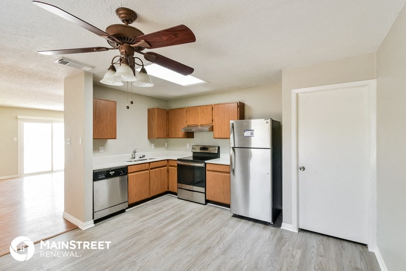 a kitchen with wooden cabinets and stainless steel appliances and a ceiling fan
