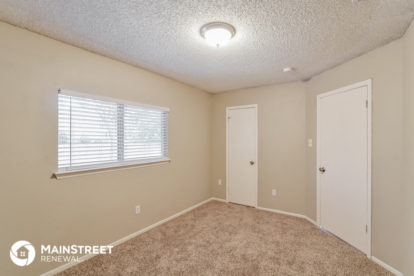 the spacious living room with carpeted flooring and a large window
