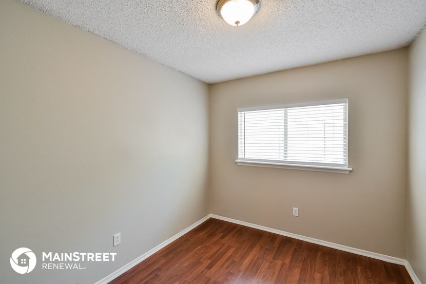 the spacious bedroom of this 2500sf home has hardwood flooring and a window
