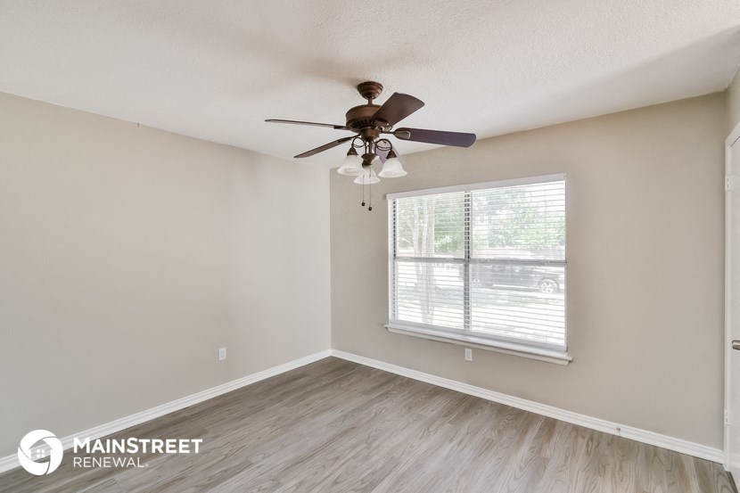 the spacious living room with ceiling fan and window