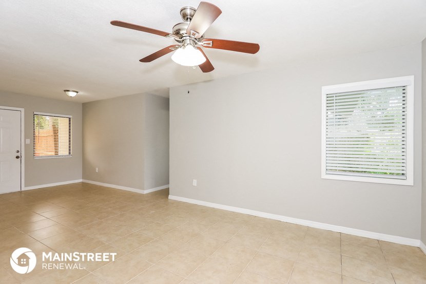 the spacious living room with ceiling fan and tile flooring