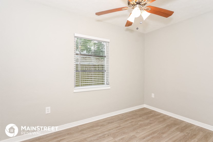 the living room of this home has a ceiling fan and a window