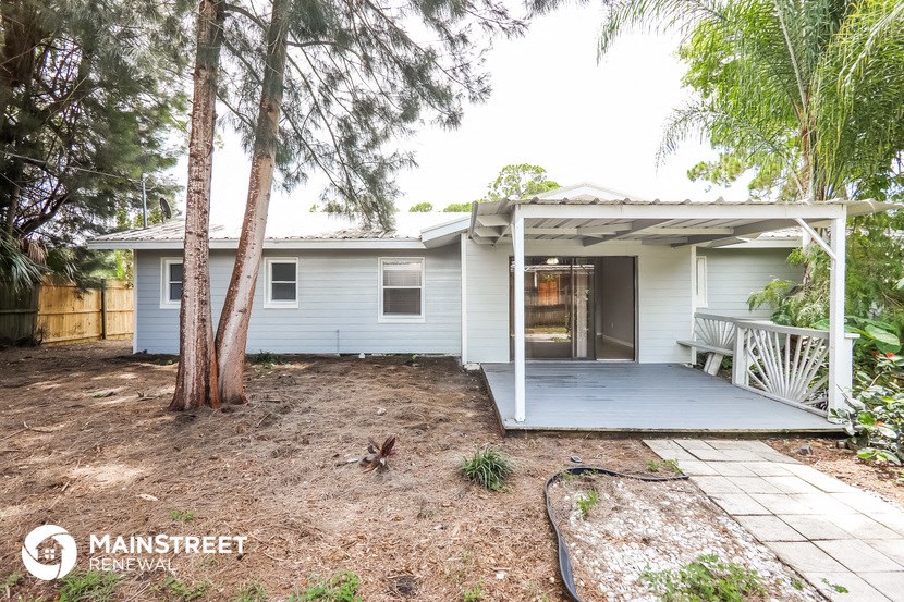 a white house with a porch and a yard with trees