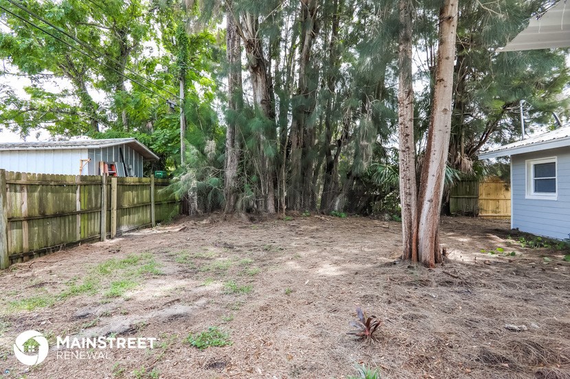 a backyard with trees and a fence and a house